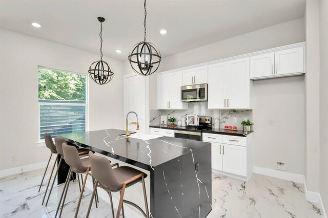 kitchen with an inviting chandelier, marble finish floor, dark countertops, and stainless steel appliances