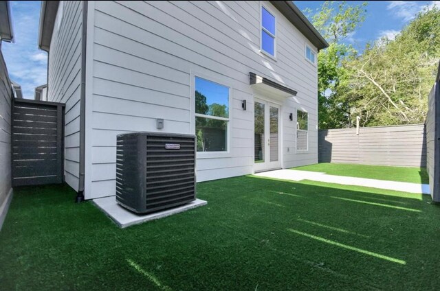 back of house featuring a fenced backyard, a yard, and cooling unit