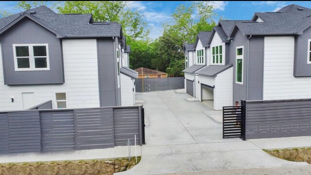 view of property exterior featuring an attached garage, driveway, a gate, and fence private yard