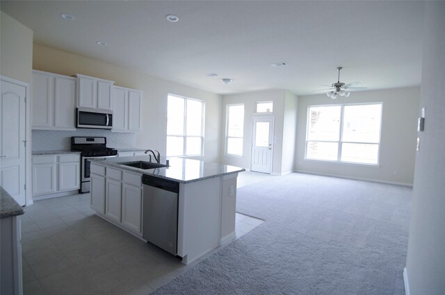 kitchen with white cabinetry, light stone counters, a sink, backsplash, and stainless steel appliances
