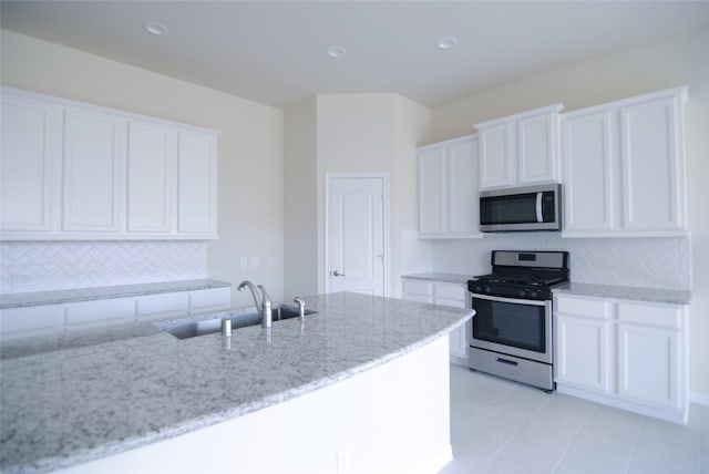 kitchen featuring backsplash, a sink, light stone counters, white cabinets, and stainless steel appliances