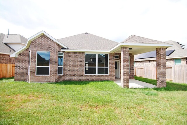 rear view of property with a lawn, brick siding, fence, and a patio area