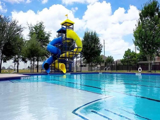 view of pool with a water slide and fence