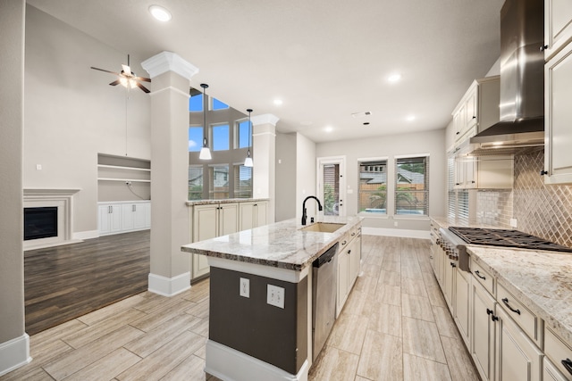 25211 Birchwood Springs Ave, Porter, TX 77365 - kitchen with wall chimney range hood, a ceiling fan, appliances with stainless steel finishes, wood finish floors, and a sink