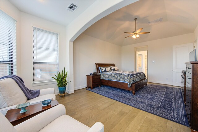 bedroom with arched walkways, baseboards, visible vents, and wood finished floors