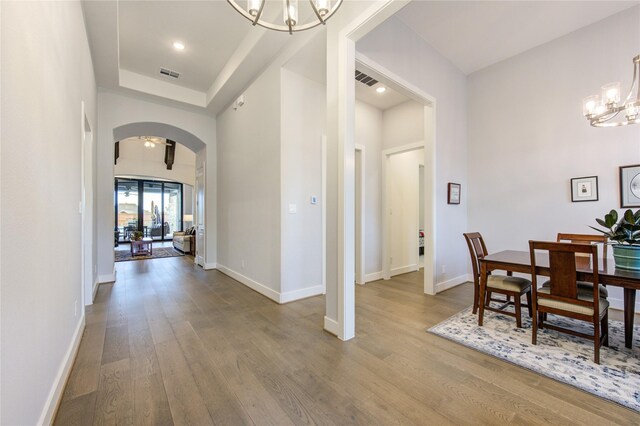 dining space featuring arched walkways, visible vents, wood finished floors, and a chandelier