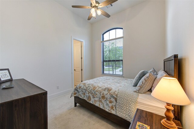 bedroom featuring visible vents, baseboards, light colored carpet, a ceiling fan, and vaulted ceiling