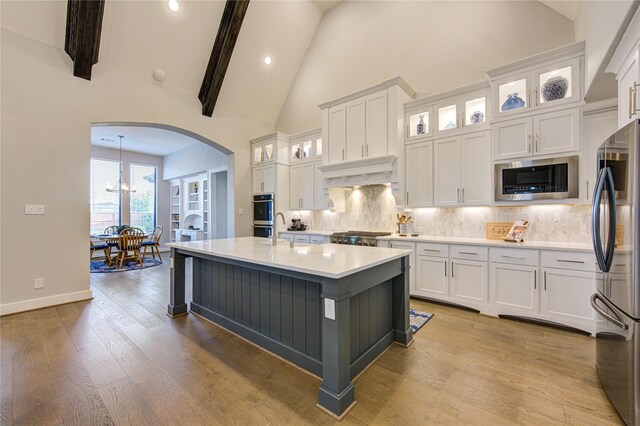 kitchen with arched walkways, white cabinetry, appliances with stainless steel finishes, and under cabinet range hood
