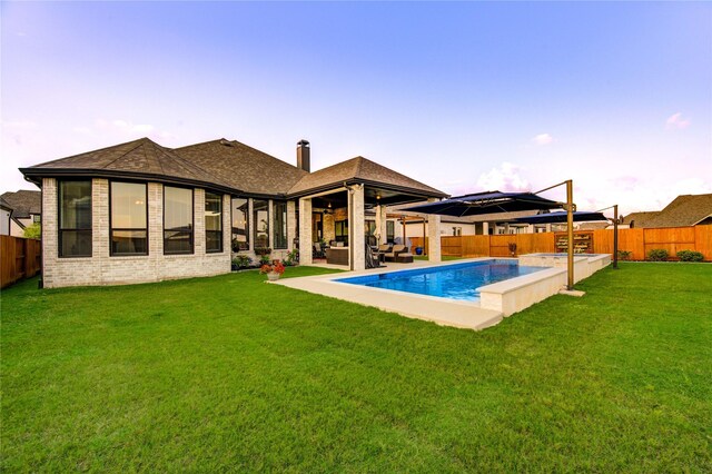back of property featuring brick siding, a fenced backyard, a lawn, and a patio