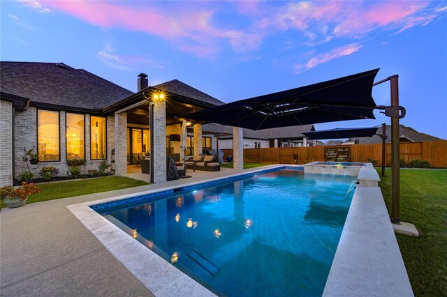pool at dusk with a pool with connected hot tub, a fenced backyard, an outdoor living space, a patio area, and a yard