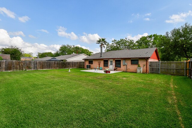 back of house featuring brick siding, a fenced backyard, a patio area, and a lawn