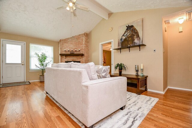 living area with vaulted ceiling with beams, ceiling fan, baseboards, and light wood-style floors
