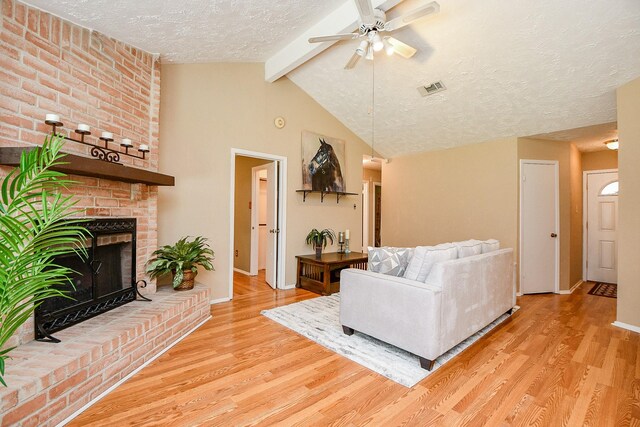 living area featuring a textured ceiling, a ceiling fan, baseboards, wood finished floors, and visible vents