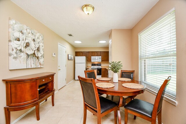 dining area featuring light tile patterned floors, baseboards, visible vents, and a healthy amount of sunlight