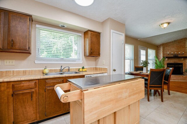 kitchen featuring a center island, a sink, light tile patterned floors, and a healthy amount of sunlight