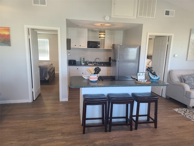 4222 Mason Dr, Galveston, TX 77554 - kitchen with freestanding refrigerator, dark countertops, visible vents, and black microwave