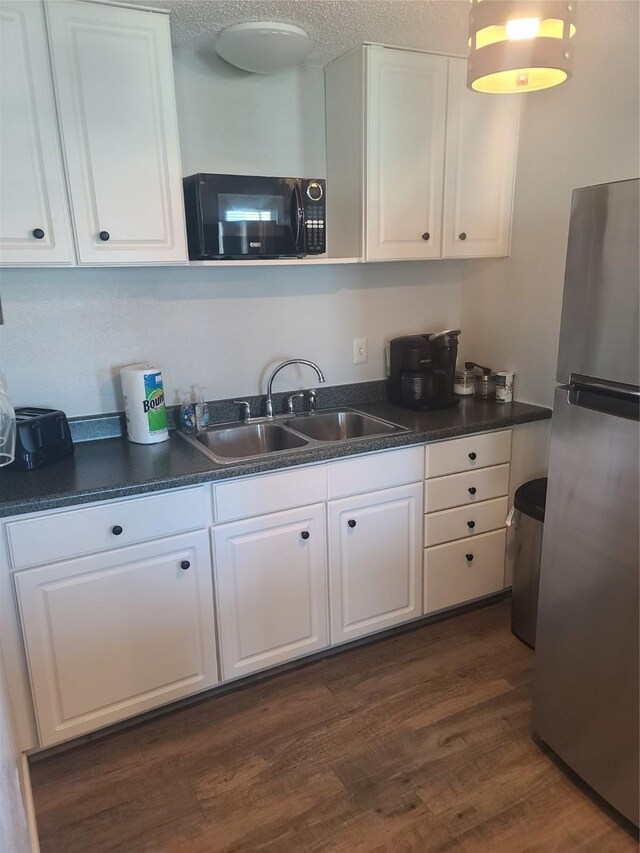 4222 Mason Dr, Galveston, TX 77554 - kitchen featuring freestanding refrigerator, black microwave, dark countertops, and a sink