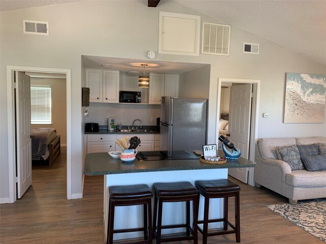 4222 Mason Dr, Galveston, TX 77554 - kitchen featuring freestanding refrigerator, dark countertops, visible vents, and high vaulted ceiling
