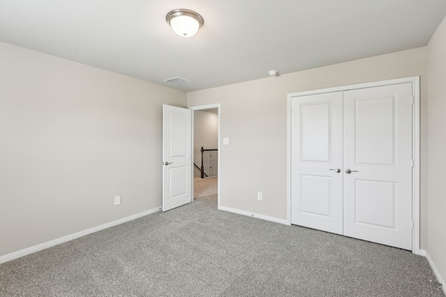 unfurnished bedroom with carpet floors, baseboards, visible vents, and a closet