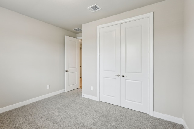 unfurnished bedroom featuring baseboards, visible vents, light carpet, and a closet