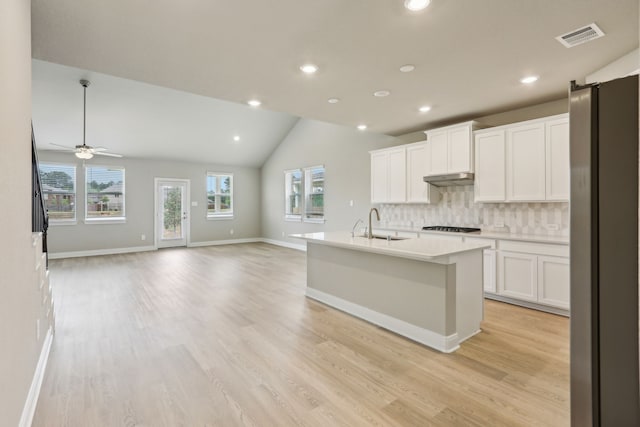 kitchen with visible vents, freestanding refrigerator, gas cooktop, under cabinet range hood, and backsplash