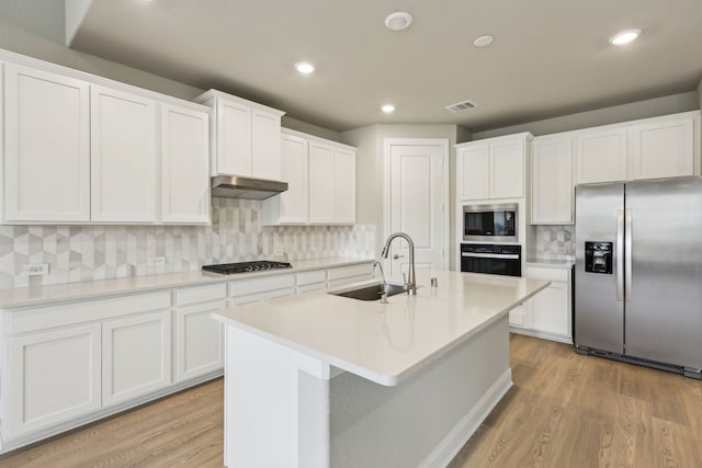 kitchen with a sink, decorative backsplash, stainless steel appliances, and light wood-type flooring