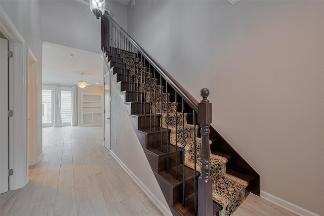 staircase featuring baseboards, ceiling fan, and wood finished floors