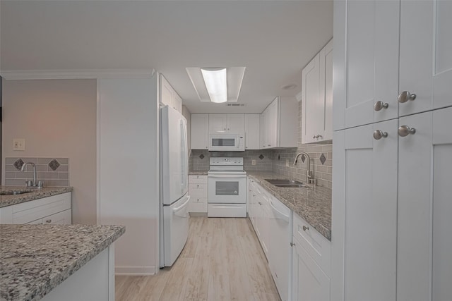 kitchen with a sink, white cabinetry, and white appliances