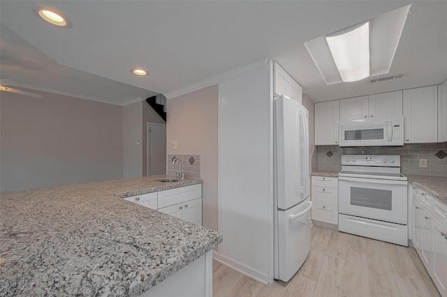 kitchen with decorative backsplash, white appliances, light stone countertops, white cabinets, and a sink
