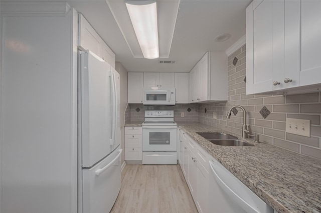 kitchen featuring decorative backsplash, light stone countertops, a sink, white appliances, and white cabinetry