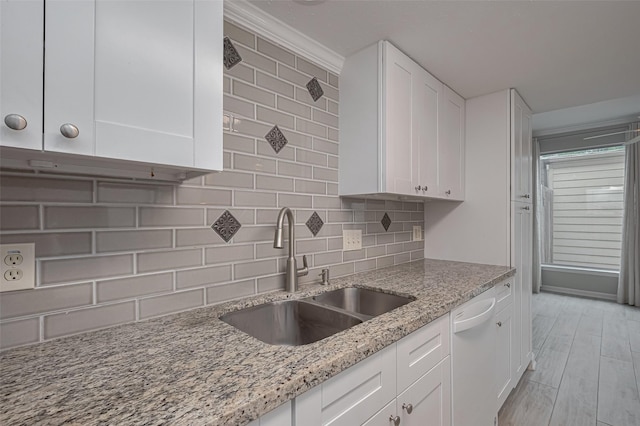 kitchen featuring a sink, dishwasher, white cabinets, and tasteful backsplash