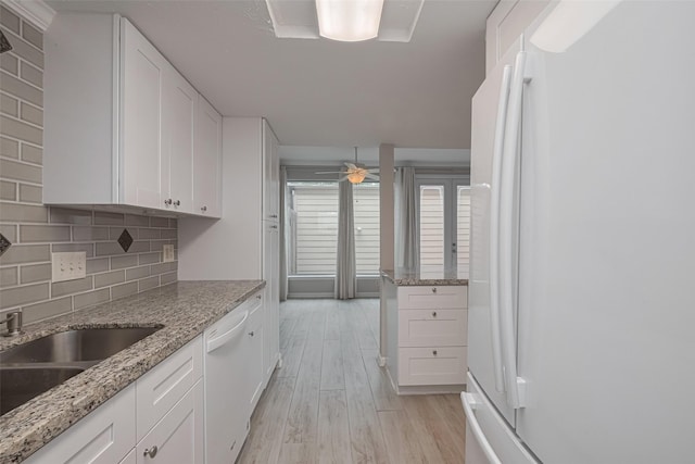 kitchen with white appliances, backsplash, white cabinets, and light wood-style flooring