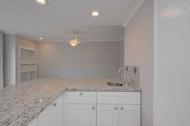 kitchen with a ceiling fan, ornamental molding, light stone countertops, recessed lighting, and a sink
