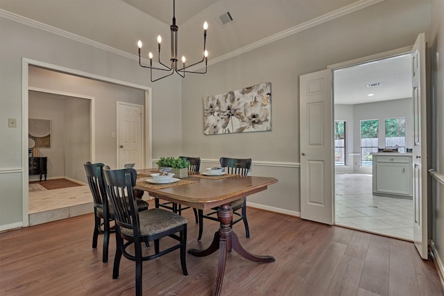 dining area with visible vents, ornamental molding, wood finished floors, and an inviting chandelier