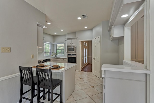 kitchen with a sink, light countertops, light tile patterned floors, a peninsula, and stainless steel appliances