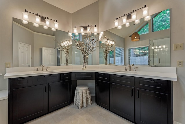 bathroom with a sink, an inviting chandelier, a tile shower, and double vanity