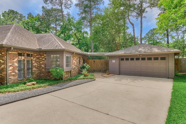 view of home's exterior featuring a garage, fence, roof with shingles, brick siding, and driveway