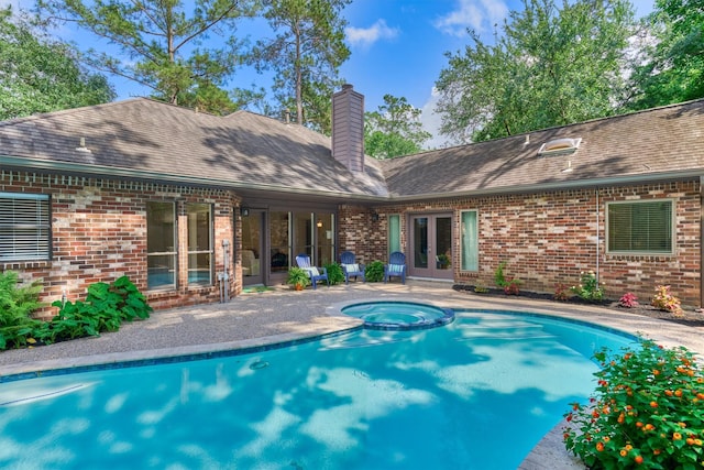 view of pool featuring a pool with connected hot tub, french doors, and a patio area
