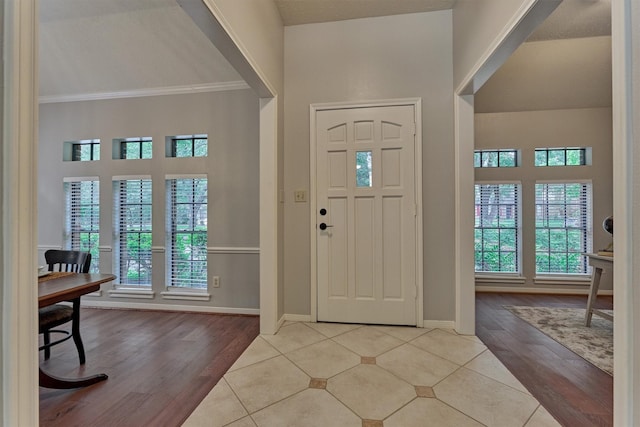 entrance foyer with a healthy amount of sunlight, baseboards, crown molding, and wood finished floors
