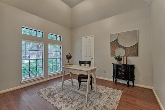 office area with baseboards, a high ceiling, and wood finished floors
