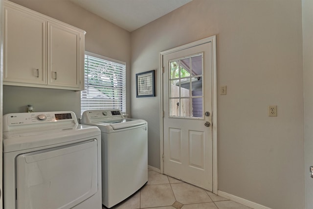 laundry room featuring light tile patterned floors, a wealth of natural light, cabinet space, and washer and dryer