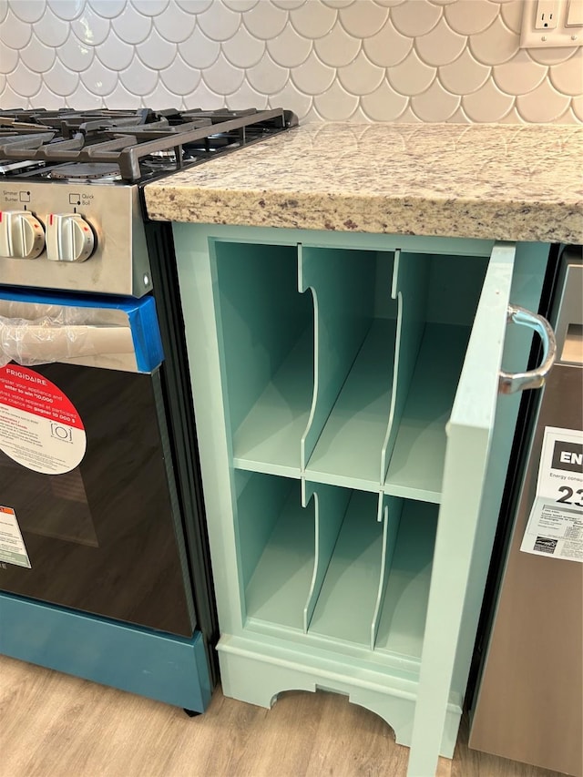 details with light wood-type flooring, green cabinetry, backsplash, and gas range