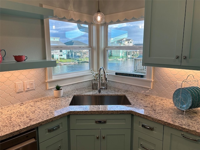 kitchen with a sink, light stone counters, tasteful backsplash, and green cabinets