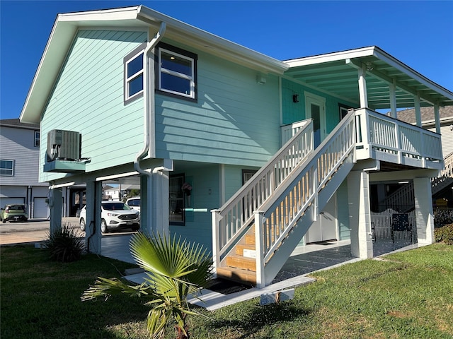 rear view of property with a lawn, stairs, and central AC