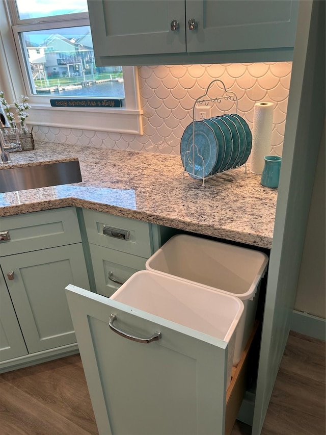 details with backsplash, light stone countertops, dark wood finished floors, and a sink