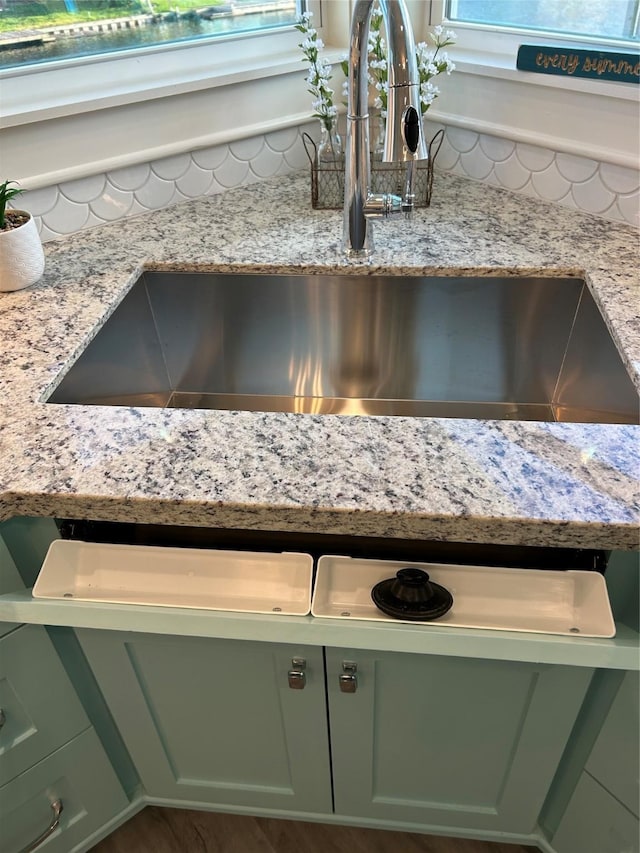 details with green cabinetry, light stone counters, and a sink