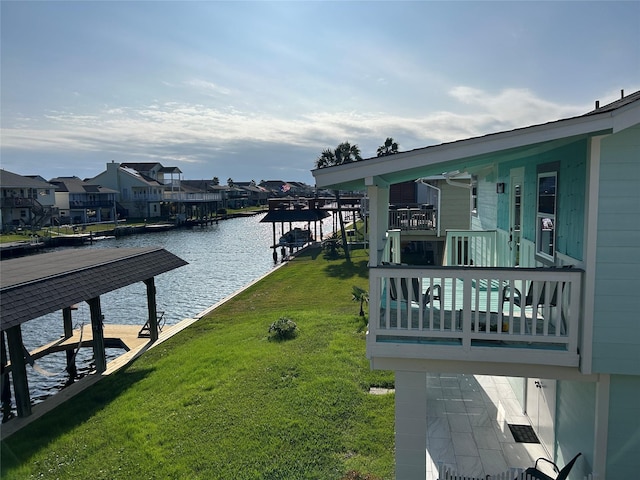 dock area with a lawn, a water view, boat lift, and a residential view