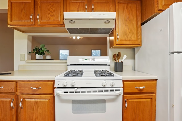 kitchen with light countertops, brown cabinets, under cabinet range hood, and white appliances