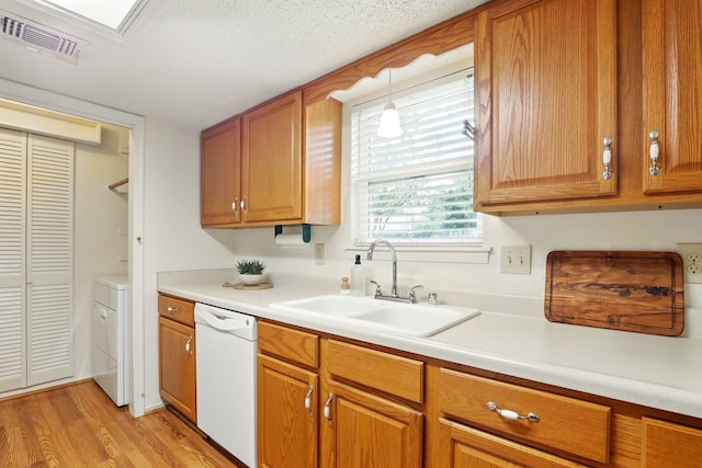 kitchen featuring visible vents, light countertops, a sink, light wood-style flooring, and dishwasher