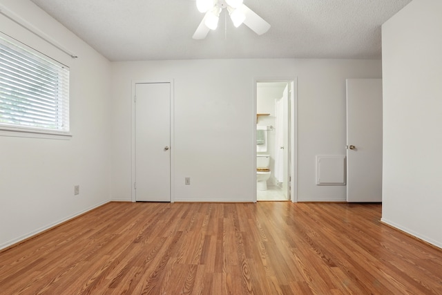 unfurnished bedroom featuring baseboards, ceiling fan, light wood finished floors, and ensuite bath